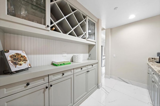bar featuring marble finish floor and baseboards