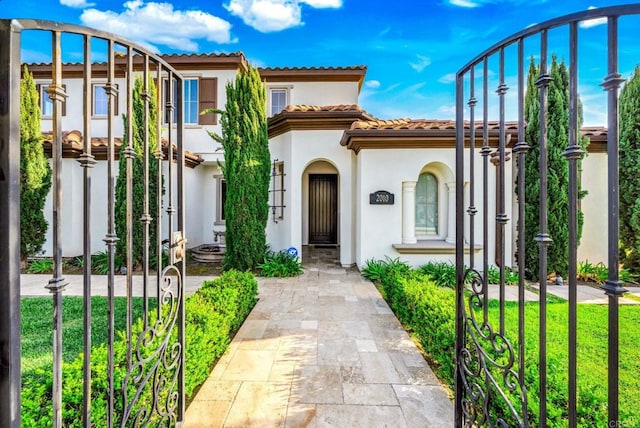 mediterranean / spanish-style house with stucco siding, a tiled roof, and a front yard