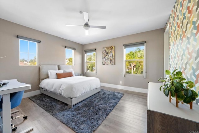 bedroom with light wood-style floors, a ceiling fan, baseboards, and multiple windows