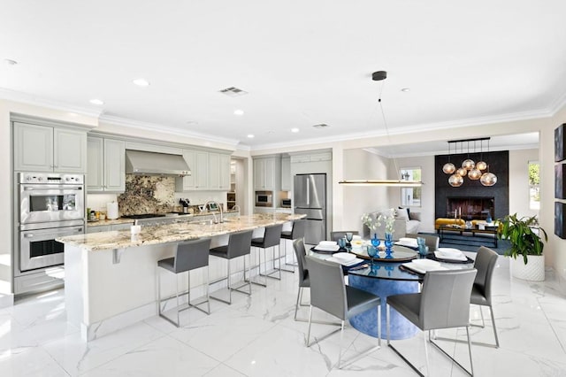 interior space with marble finish floor, stainless steel appliances, visible vents, wall chimney exhaust hood, and crown molding