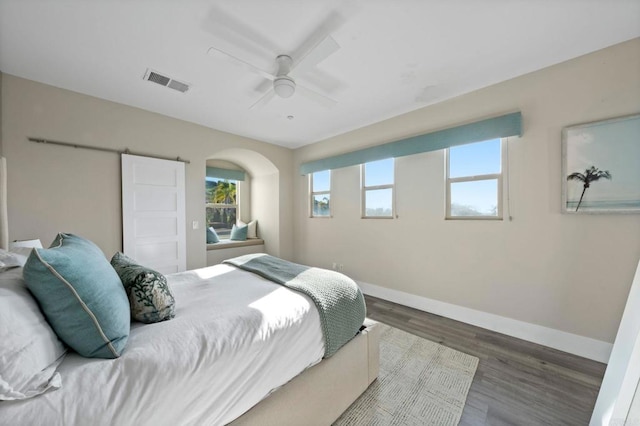 bedroom with wood finished floors, visible vents, a ceiling fan, arched walkways, and baseboards