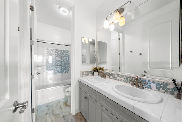 bathroom with shower / bath combination with glass door, toilet, a sink, and double vanity
