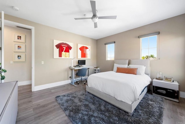 bedroom with wood finished floors, visible vents, baseboards, and ceiling fan