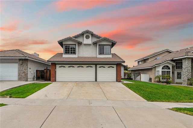 traditional home featuring fence, a tile roof, stucco siding, a front yard, and driveway