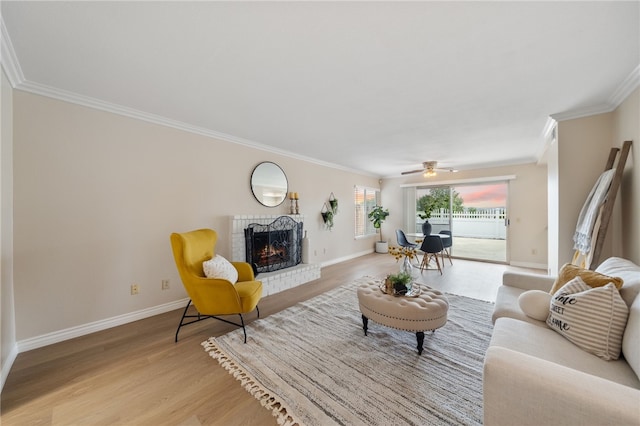 living area with crown molding, baseboards, light wood-style floors, and a fireplace