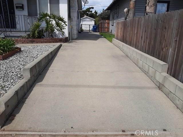 339 E 64th St E, Los Angeles, CA 90003 - view of patio featuring fence, concrete driveway, and an outbuilding
