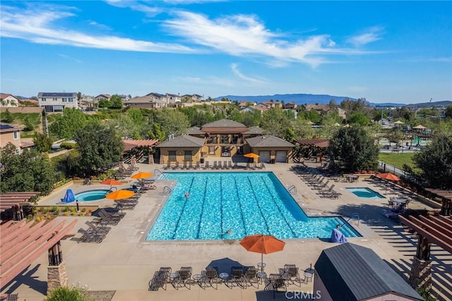 community pool with a patio, a mountain view, fence, and a community hot tub