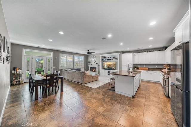 kitchen with recessed lighting, freestanding refrigerator, dark countertops, a sink, and open floor plan