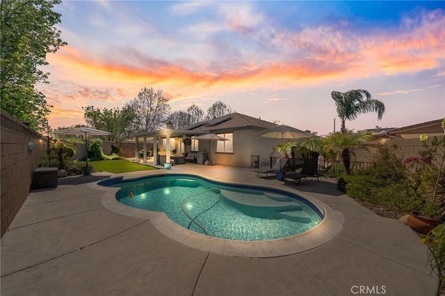 pool at dusk featuring a fenced in pool, a patio area, and a fenced backyard