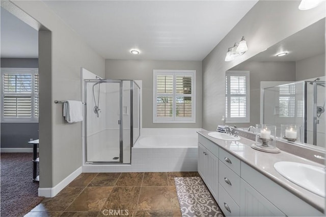 full bathroom with double vanity, a garden tub, a stall shower, and a sink
