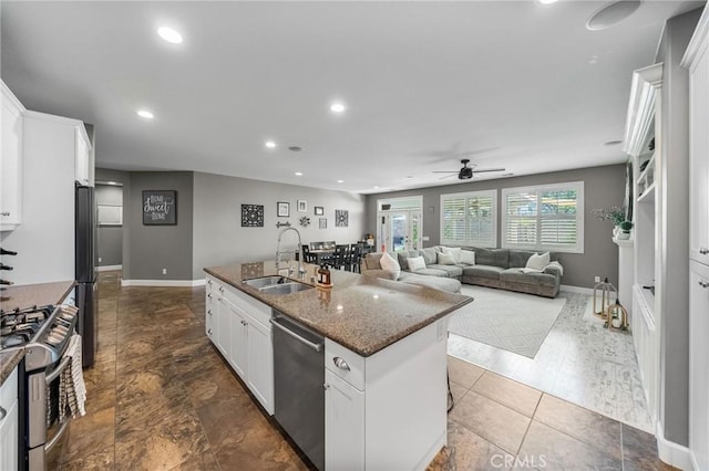 kitchen featuring dark stone countertops, white cabinets, a sink, ceiling fan, and stainless steel appliances