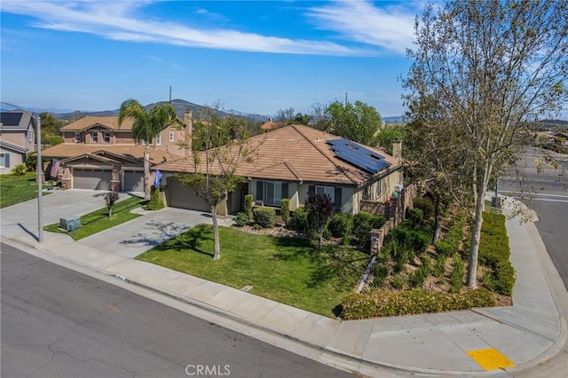 ranch-style home featuring a garage, solar panels, a tile roof, driveway, and a front lawn