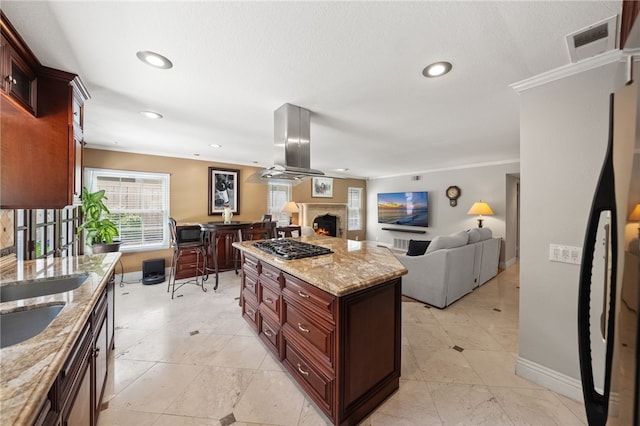 1441 San Almada Rd, Corona, CA 92882 - kitchen featuring ornamental molding, island exhaust hood, baseboards, visible vents, and a lit fireplace