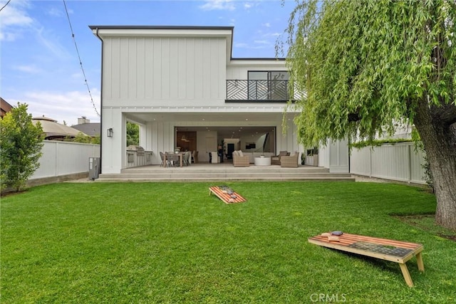 back of property featuring a fenced backyard, a yard, a balcony, and an outdoor hangout area