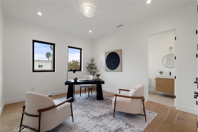 office space with baseboards, light wood-style floors, and recessed lighting