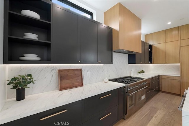 kitchen with light stone counters, light wood-style flooring, dark cabinetry, and gas cooktop