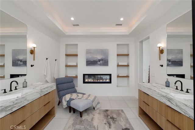 bathroom featuring visible vents, a glass covered fireplace, a sink, and built in shelves