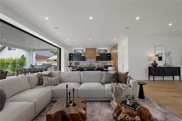 living room with baseboards, recessed lighting, and light wood-style flooring