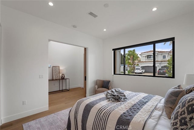 bedroom with baseboards, wood finished floors, visible vents, and recessed lighting