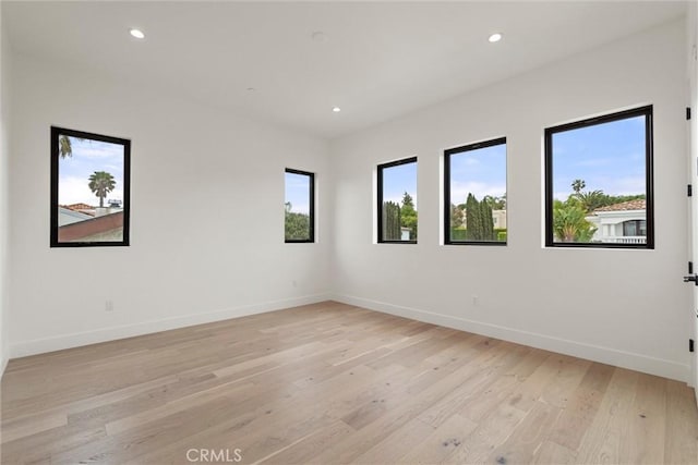 spare room featuring recessed lighting, light wood-style floors, and baseboards