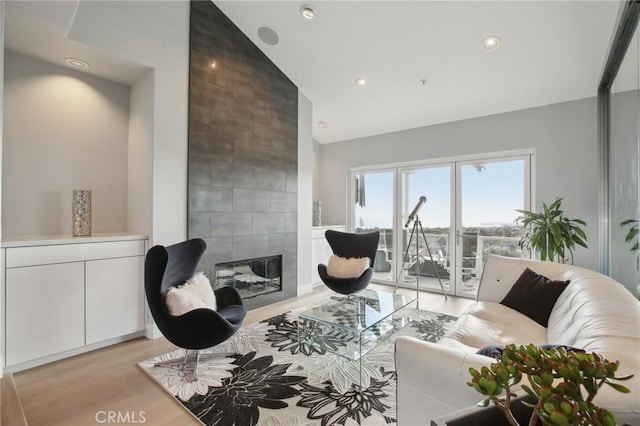 living area featuring recessed lighting, high vaulted ceiling, light wood-style flooring, and a fireplace