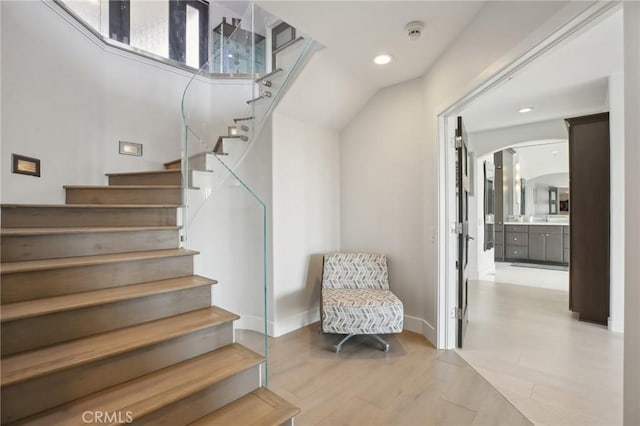 staircase featuring recessed lighting, arched walkways, baseboards, and wood finished floors