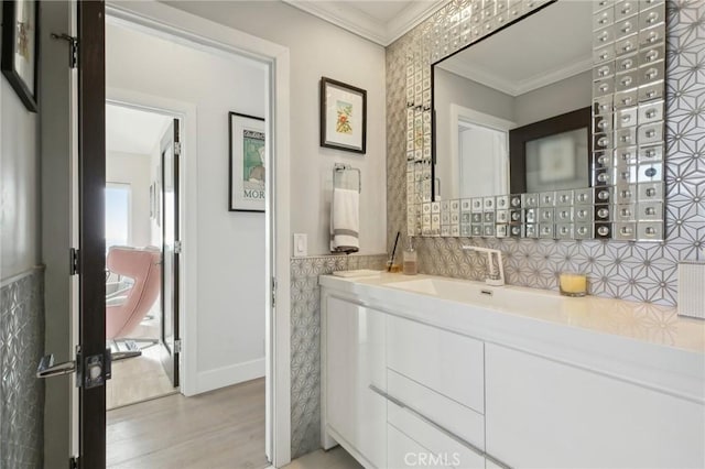 bathroom with wainscoting, vanity, baseboards, wood finished floors, and ornamental molding