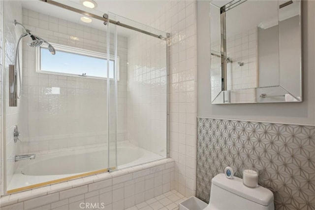 full bath with tile walls, tiled shower / bath, a wainscoted wall, and toilet