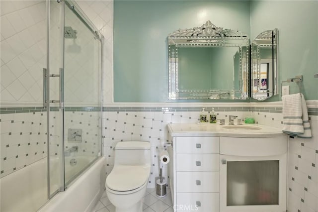 full bath with vanity, toilet, enclosed tub / shower combo, a wainscoted wall, and tile walls
