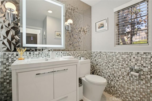 bathroom with toilet, tile walls, and vanity
