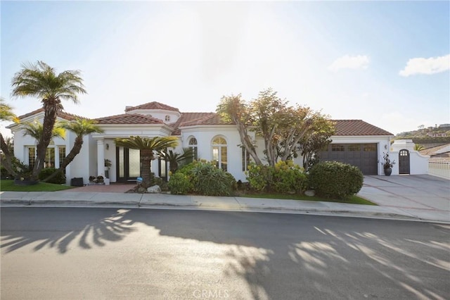 mediterranean / spanish-style home with a garage, stucco siding, driveway, and a tiled roof