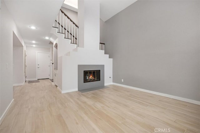 23875 Catamaran Way Unit 51, Laguna Niguel, CA 92677 - unfurnished living room featuring light wood-style floors, stairway, a high ceiling, recessed lighting, and a fireplace with flush hearth
