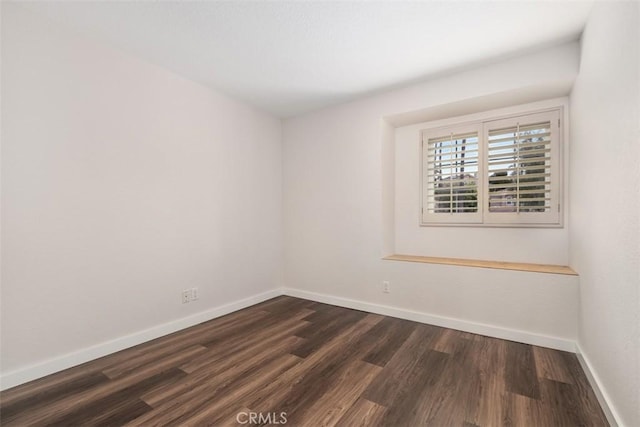 unfurnished room with baseboards and dark wood-type flooring