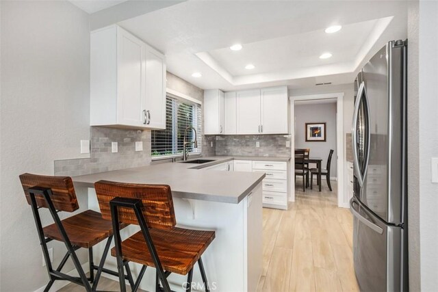 23875 Catamaran Way Unit 51, Laguna Niguel, CA 92677 - kitchen with freestanding refrigerator, a breakfast bar, backsplash, a peninsula, and light wood-style flooring