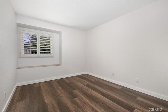 unfurnished room featuring baseboards and dark wood-style floors