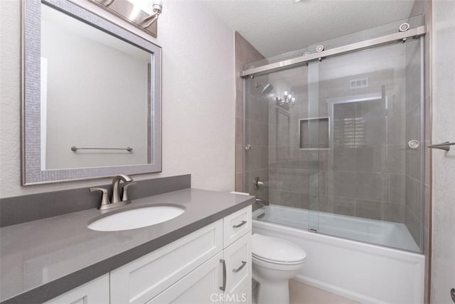 bathroom featuring toilet, vanity, bath / shower combo with glass door, and a textured ceiling
