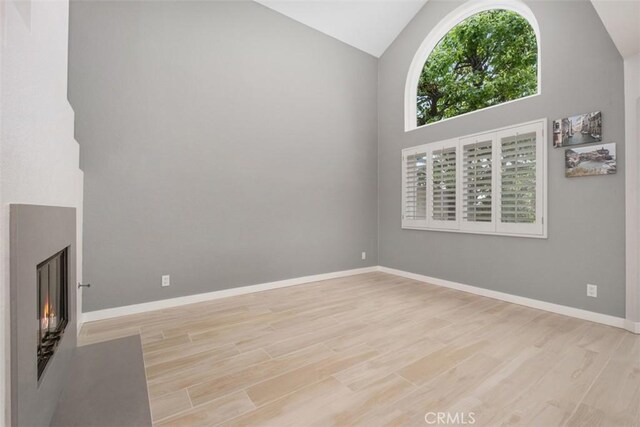 23875 Catamaran Way Unit 51, Laguna Niguel, CA 92677 - unfurnished living room featuring high vaulted ceiling, wood finished floors, and a lit fireplace