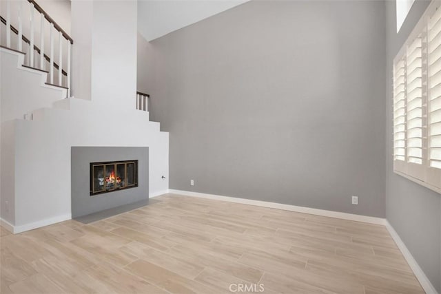 23875 Catamaran Way Unit 51, Laguna Niguel, CA 92677 - unfurnished living room featuring wood finished floors, stairway, a high ceiling, and a glass covered fireplace