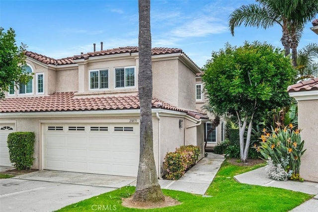 mediterranean / spanish house with an attached garage, a tiled roof, driveway, and stucco siding