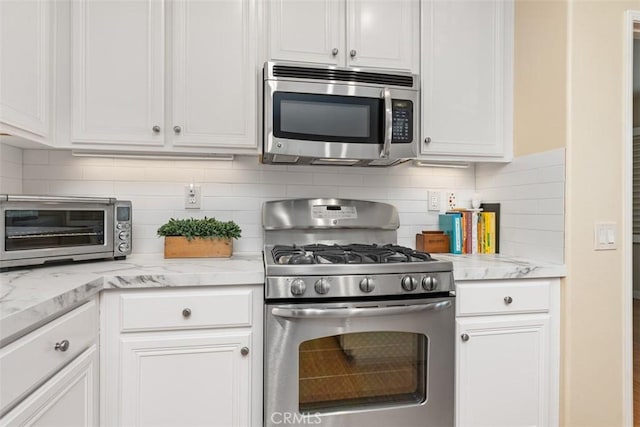 kitchen featuring tasteful backsplash, white cabinetry, a toaster, and stainless steel appliances