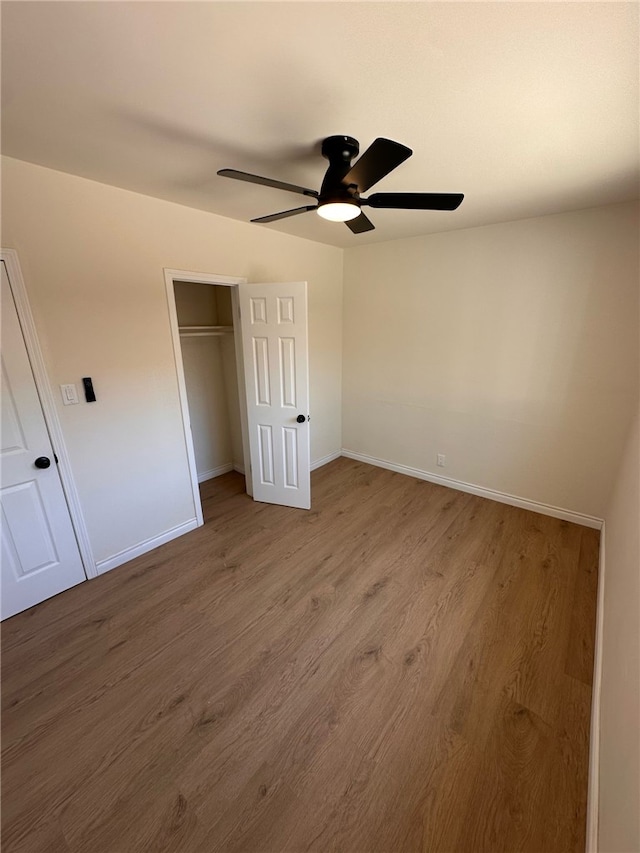 unfurnished bedroom featuring baseboards, ceiling fan, wood finished floors, and a closet