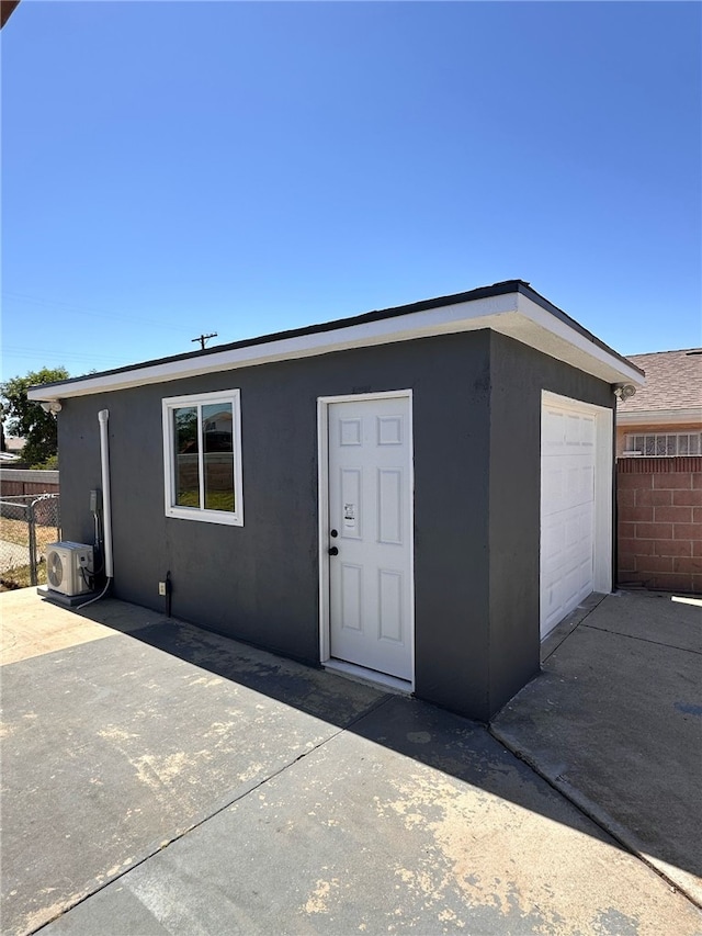 view of outdoor structure featuring a garage, ac unit, and fence