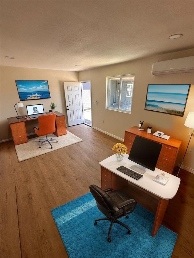 office area featuring baseboards, an AC wall unit, and wood finished floors