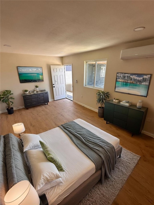 bedroom featuring baseboards, a wall mounted air conditioner, and wood finished floors