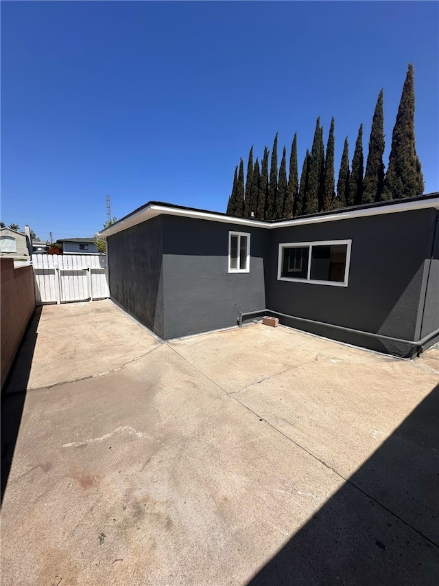 rear view of property with fence, a patio area, and stucco siding