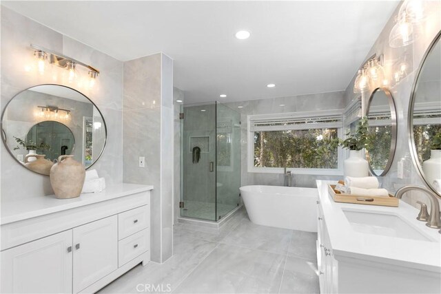 31 Terraza Del Mar, Dana Point, CA 92629 - full bathroom featuring two vanities, tile walls, a freestanding tub, a shower stall, and marble finish flooring