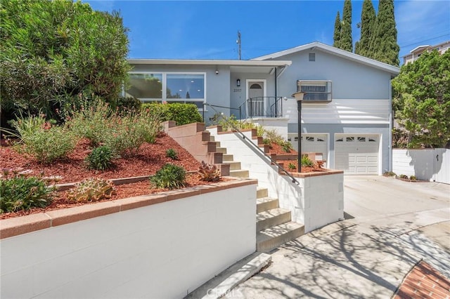 ranch-style home featuring a wall unit AC, stucco siding, driveway, stairs, and an attached garage