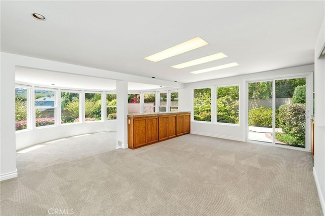 unfurnished sunroom with a wealth of natural light, carpet floors, and baseboards