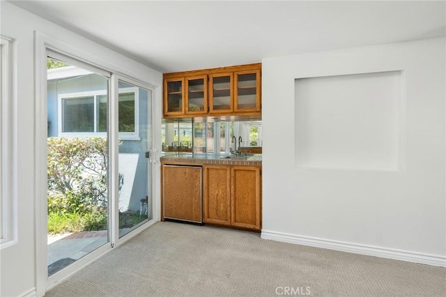 bar featuring a sink, light colored carpet, and baseboards