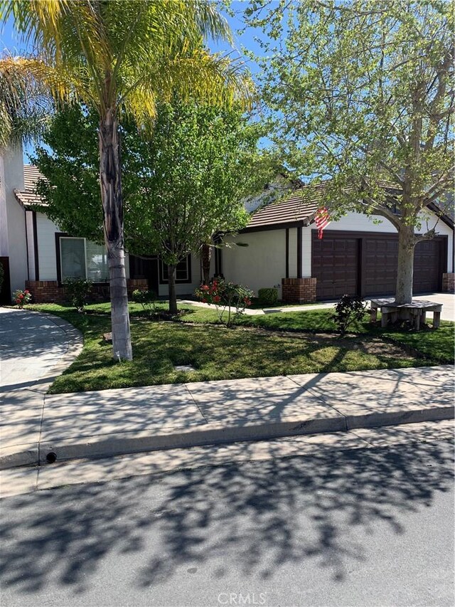 18810 Oakview Way, Lake Elsinore, CA 92530 - view of front of house featuring a tile roof, driveway, a garage, a front lawn, and brick siding
